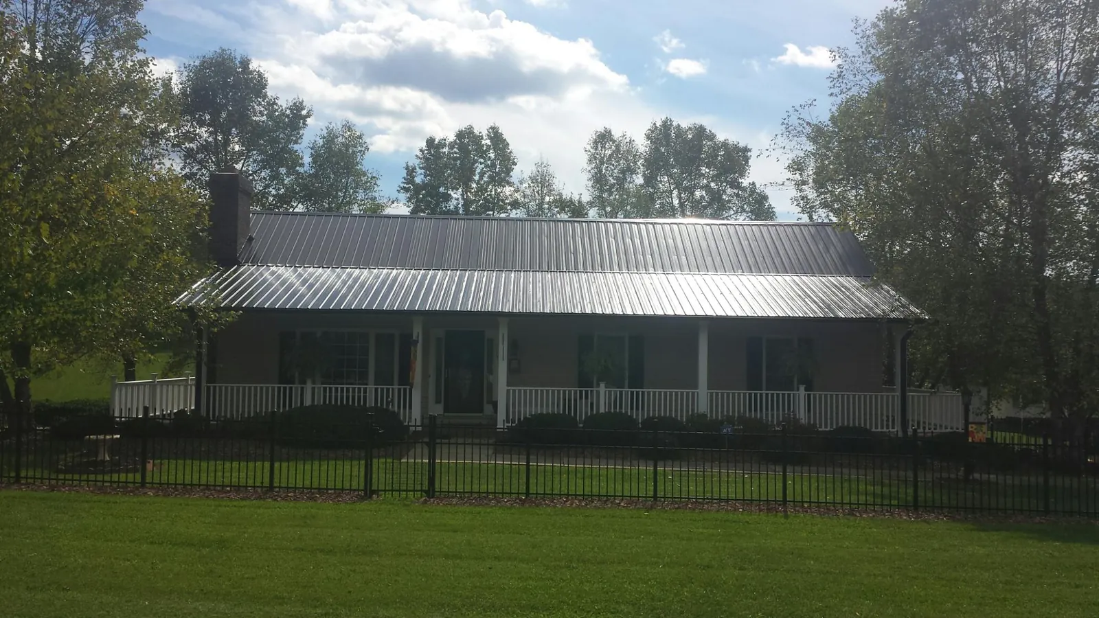 Gray metal roof on a brick ranch with a full width front porch — Gutter Guard Installation work by our crew in Elgin