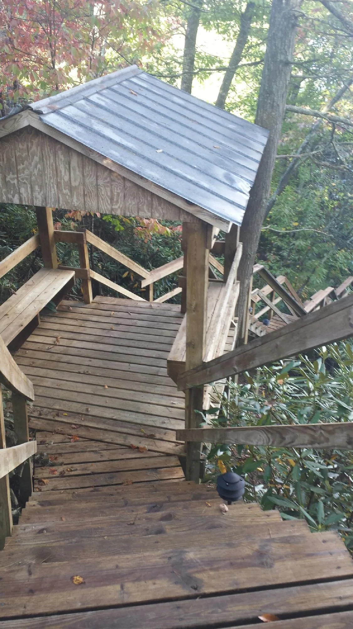 Metal roofed shelter over wooden steps on a wooded walkway — Skylight Repair & Installation work by our crew in Elgin