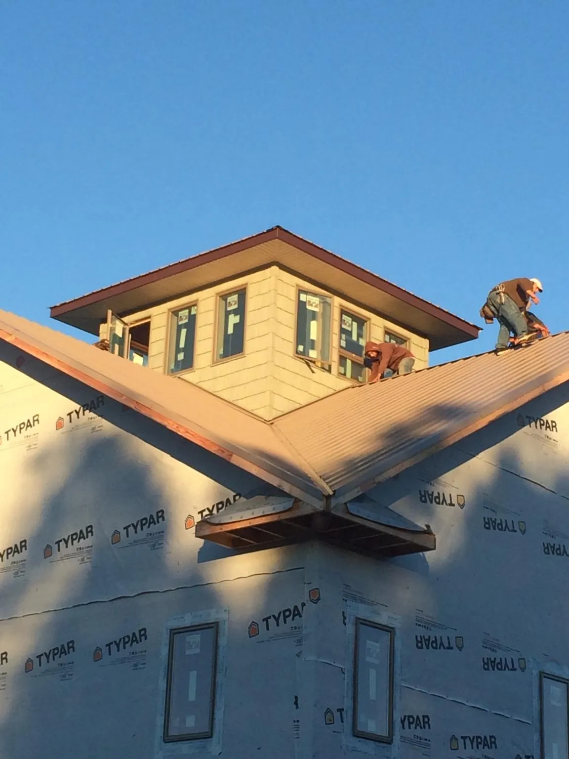 Roofers working around a rooftop cupola on a new metal roof at sunset — Roof Waterproofing in Elgin by Roofing Brothers